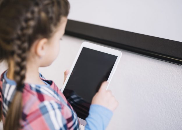 inan yar oo gacanta ku haysa tablet ama ipad oo ay ku dhaygagto